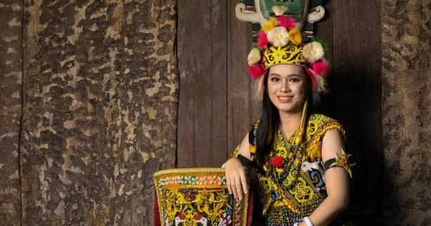 Perempuan Dayak mengenakan pakaian adat tradisional Ta'a dengan hiasan bulu burung enggang