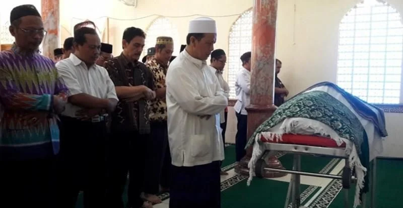 Seorang pria memimpin doa di depan makam sebagai bentuk penghormatan terakhir