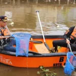 Personel Polresta Banjarmasin dan warga sedang bergotong royong membersihkan Sungai Pemurus dari sampah.