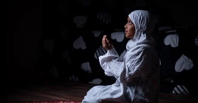 Seorang anak sedang berdoa sebelum mulai belajar di meja sekolah